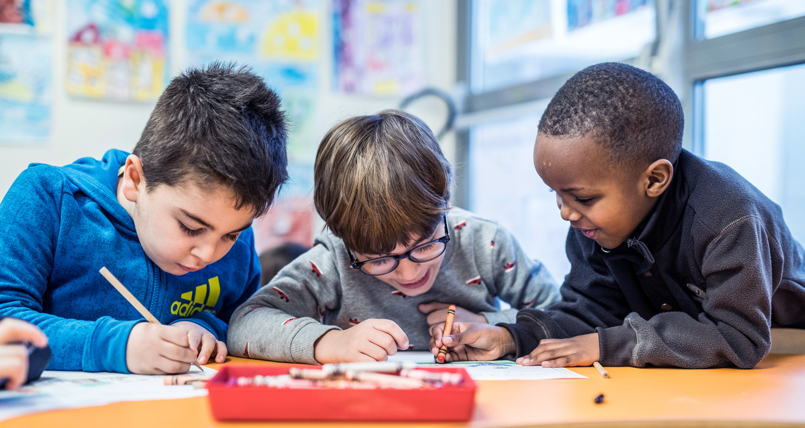 Three young students are working in English and French in a classroom