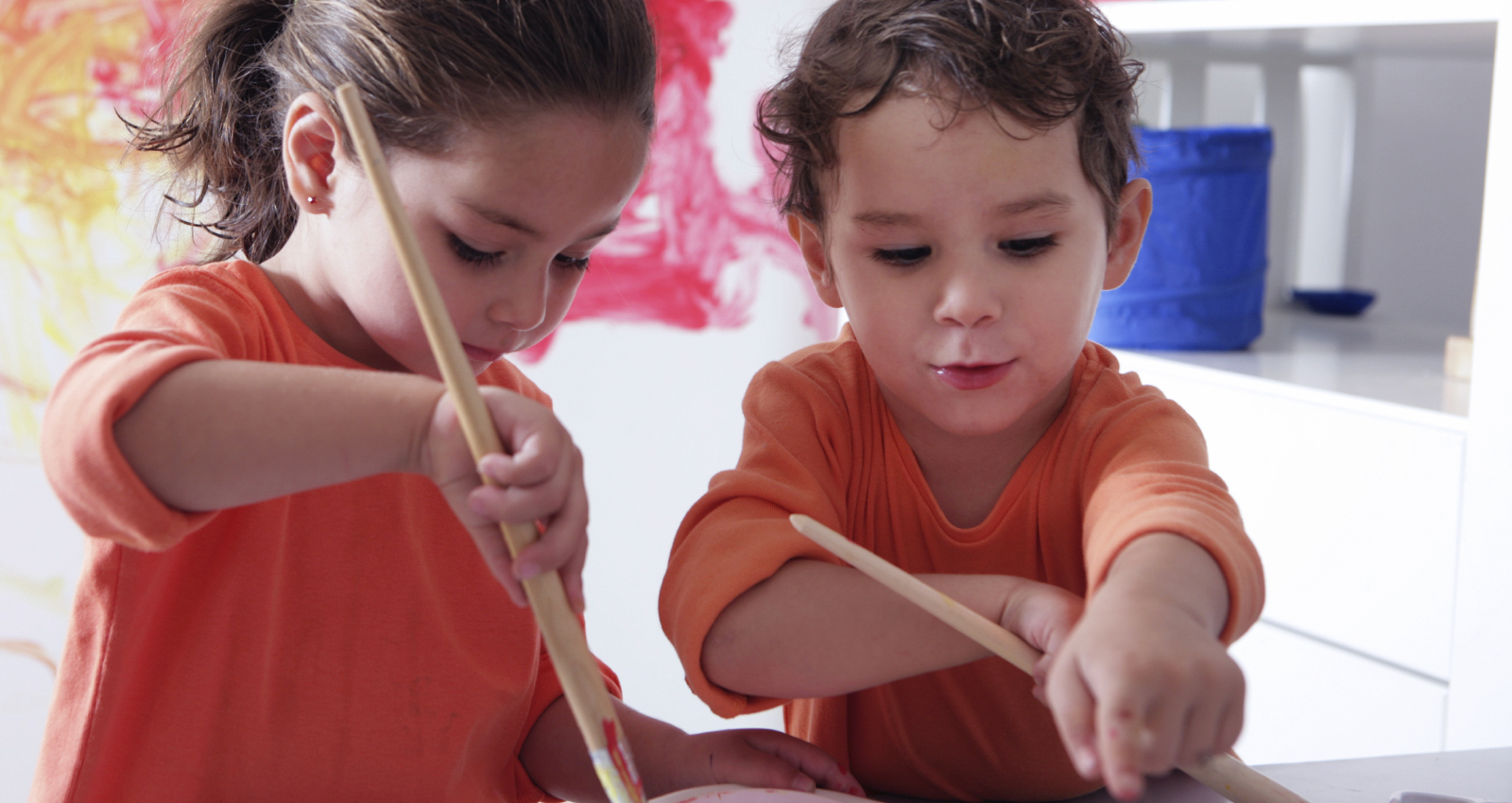 Two young children who are painting in a classroom