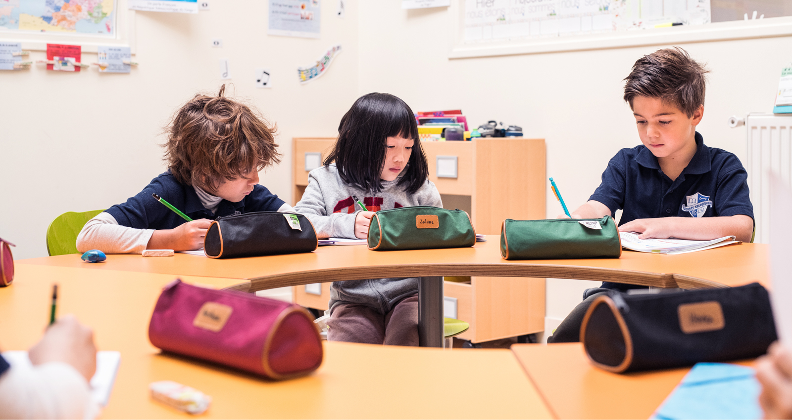 Three students are working in a bilingual classroom