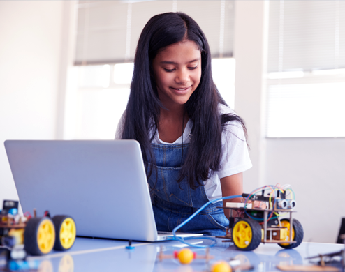 Middle school girl in technology using computers to create and code robots