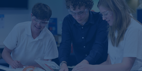 Three students in a science classroom with protective glasses