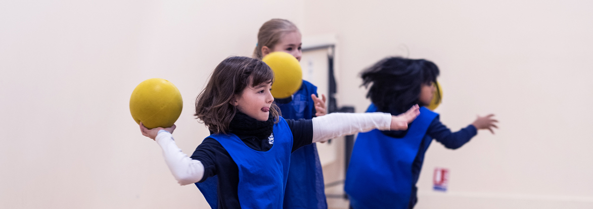 Trois enfants de primaire pendant un cours de sport lancent un ballon