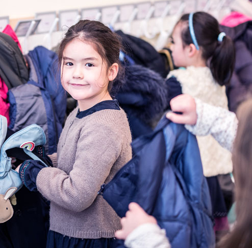 Young bilingual student taking off her coat