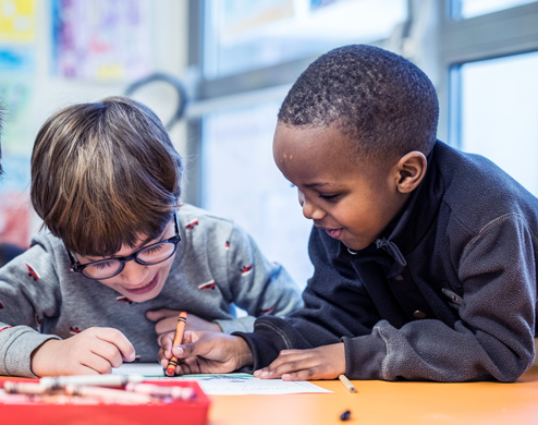 Two students are coloring drawings in a book