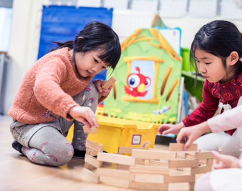 Une enfant en maternelle joue avec des jouets en bois